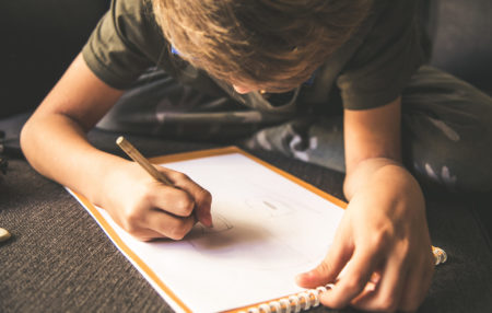 photo of a child drawing a picture on a notepad