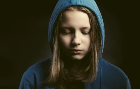 child in a hoodie with their eyes closed