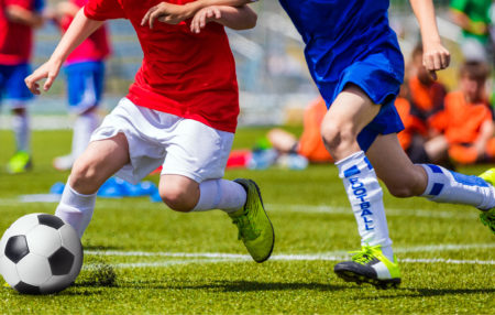 soccer players from different teams chasing after the soccer ball