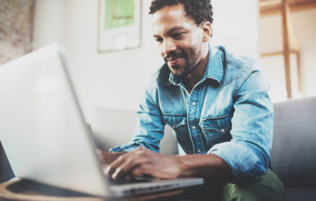 man sitting on a couch using a laptop