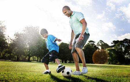 father and son practicing soccer together