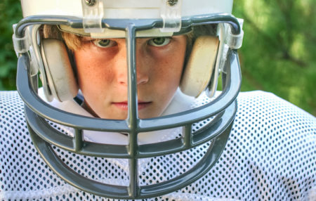 photo of a youth football player in a helmet staring determinedly at the camera