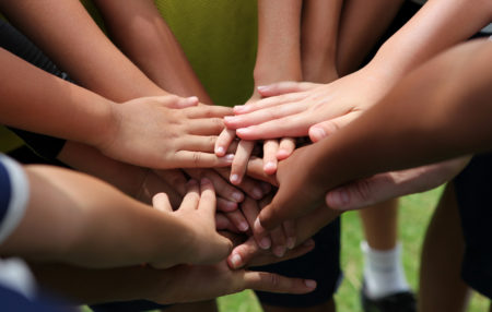 group of young people with their hands together in a circle