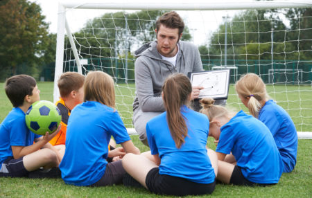 photo of a coach showing his youth soccer team a game plan