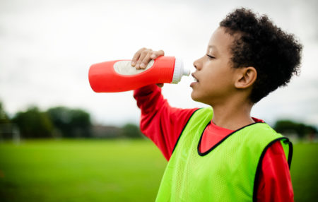 photo of a child playing sports and drinking from a water bottle